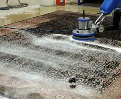 Professional rug cleaning with a rotary floor machine and shampoo foam, deep-cleaning an area rug, in Bakersfield, CA.