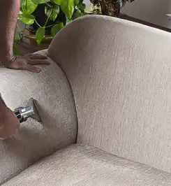 Professional upholstery cleaner deep-cleaning a fabric sofa with a handheld extraction tool and hose Bakersfield, CA.